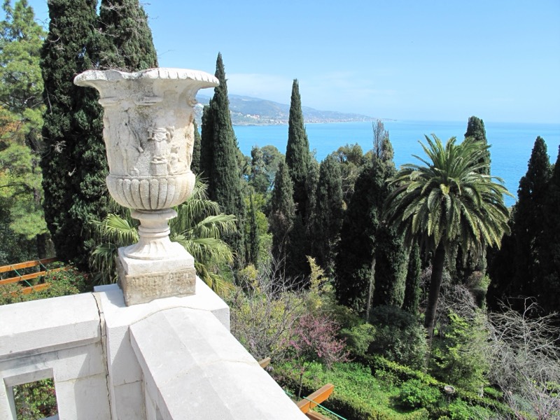Terrazza dei Giardini Botanici Hanbury alla Mortola con vaso in pietra, cipressi, palme e mare